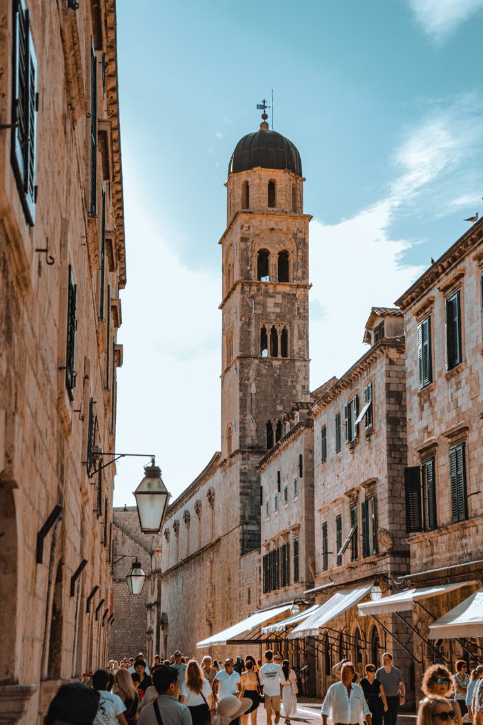 Historic street scene with church tower in Dubrovnik, capturing Croatia's Mediterranean charm.