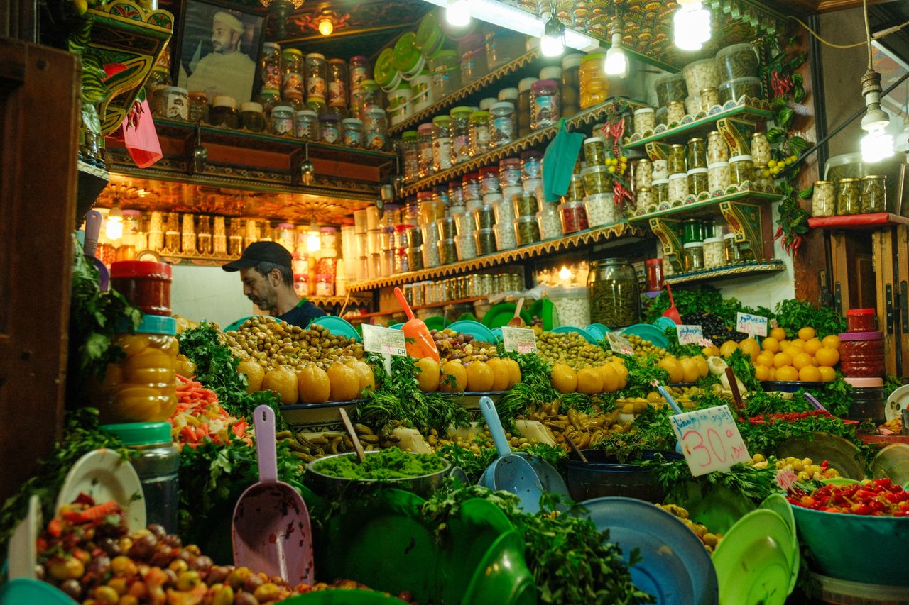 Colorful array of spices and produce in a bustling market stall in Fes, Morocco.