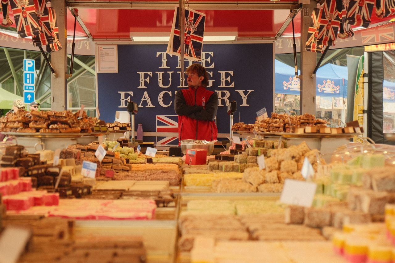 A vibrant selection of fudge displayed at an outdoor market stall, featuring British flags and signage.