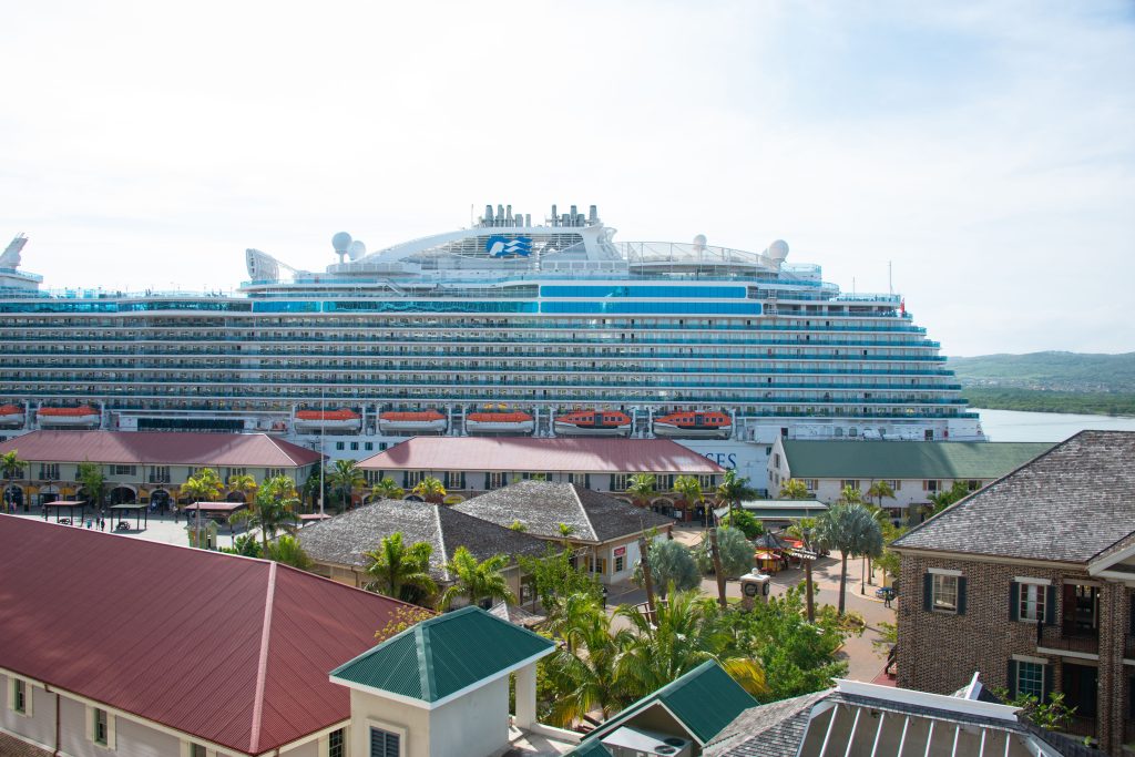 Large cruise ship docked at a tropical Caribbean island port for shore excursions