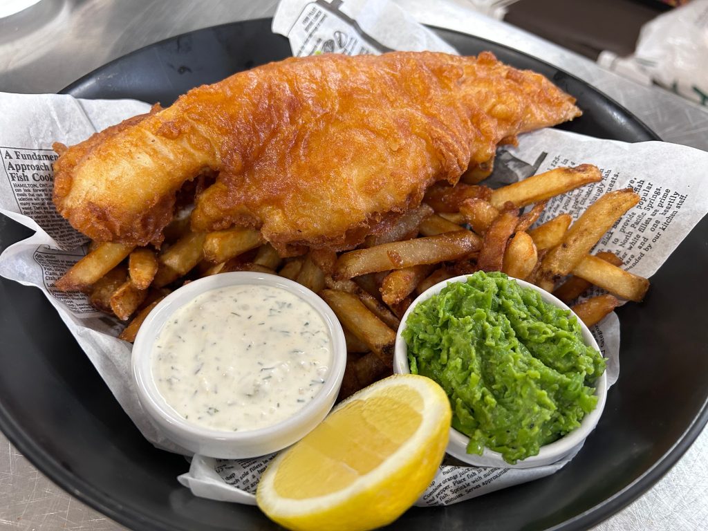 Traditional British fish and chips with a pint of ale inside a cozy London pub.