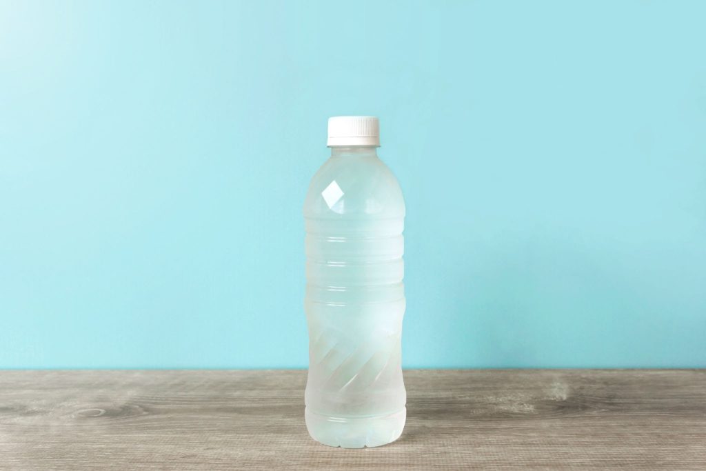 A factory-sealed plastic water bottle on a wooden table representing safe drinking water in Bali