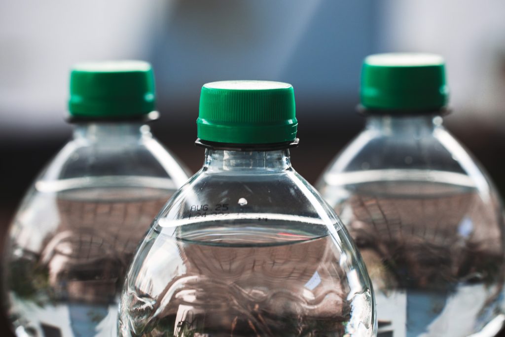 A traveler holding a sealed plastic bottled water in an outdoor Indian market to ensure food safety.