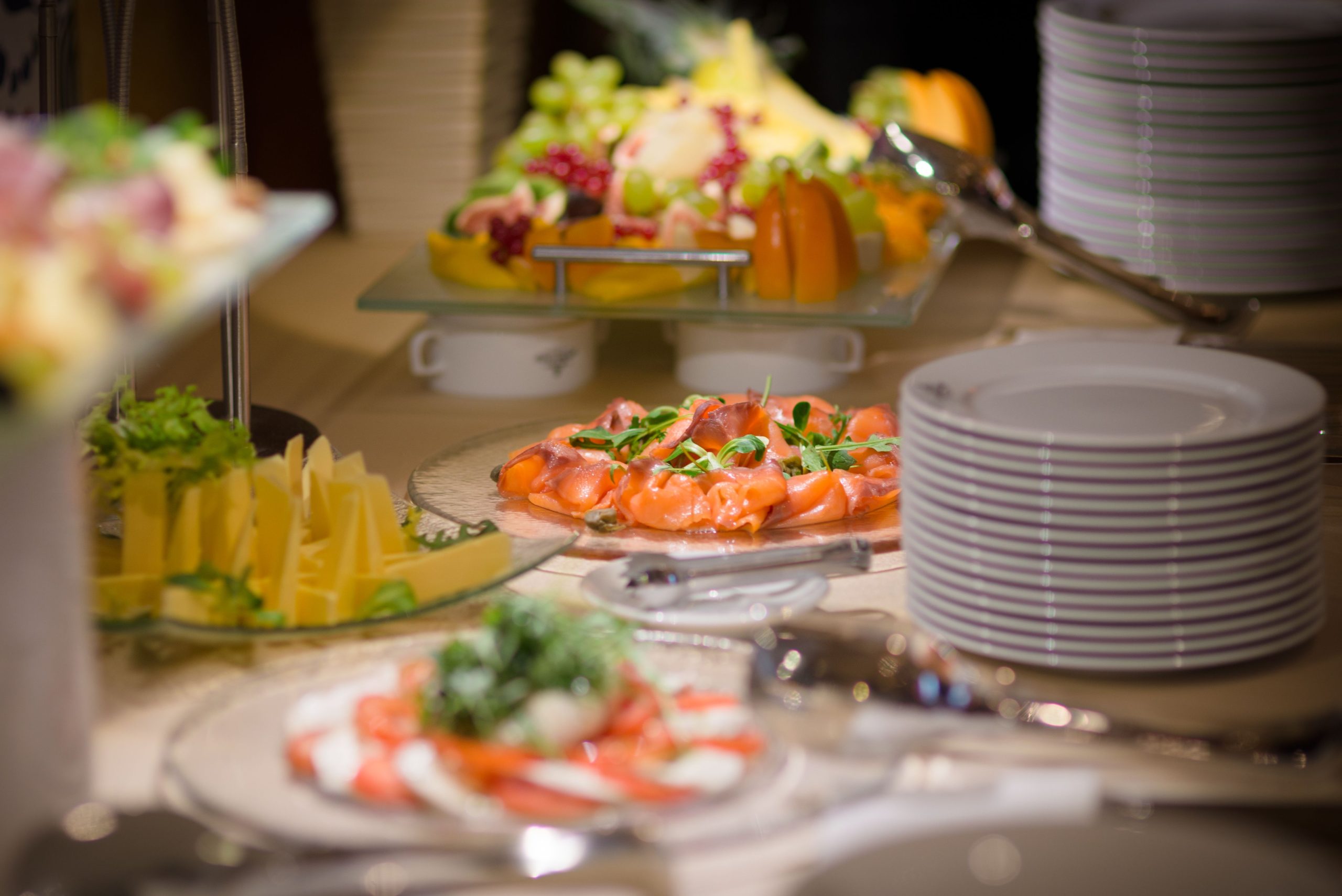 A busy premium buffet dining line inside a luxury cruise ship with passengers selecting food.