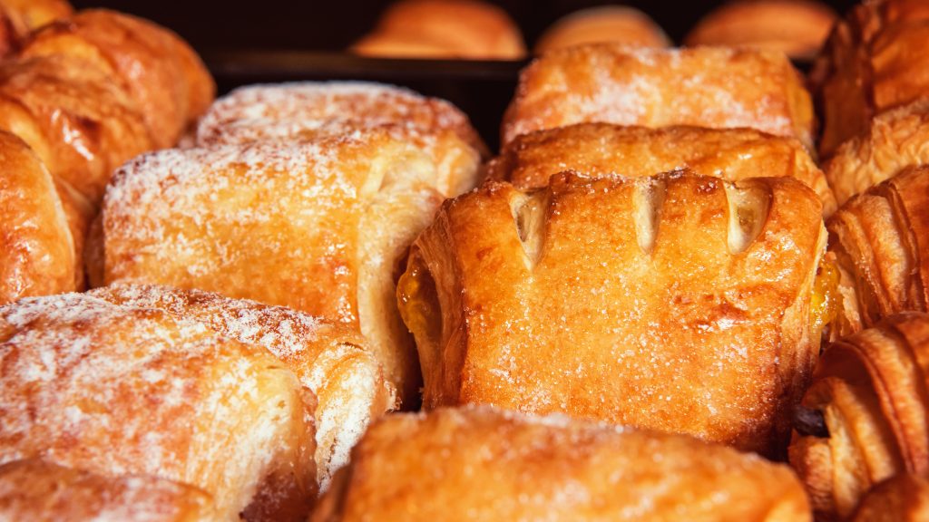 Freshly fried hot beignets piled high with a thick layer of white powdered sugar on a plate