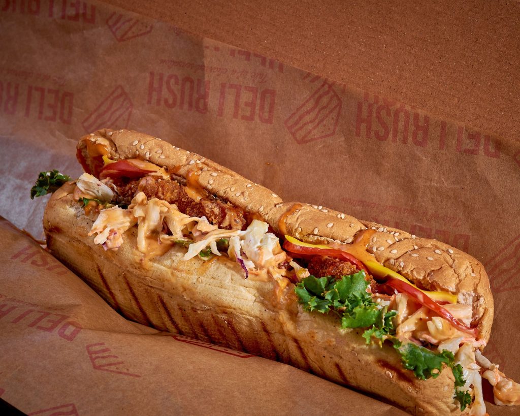 A massive overstuffed sub sandwich packed with meat lettuce and tomatoes on crisp French bread